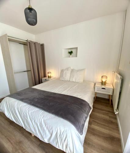 a bedroom with a large white bed with two tables at La Petite Vitesse in La Flèche