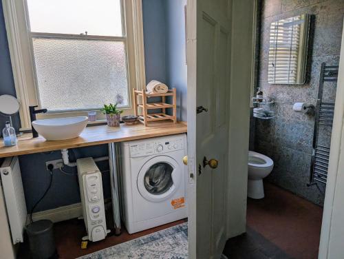 a bathroom with a washing machine and a sink at The Writer's Retreat Ground Floor Apartment in Holt