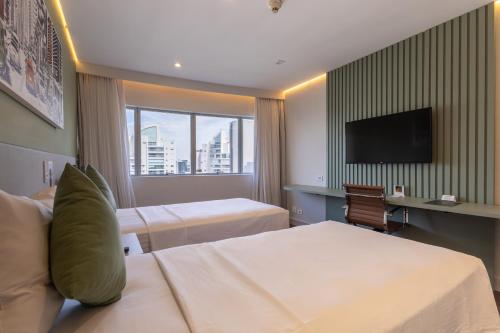 a hotel room with two beds and a flat screen tv at Hotel Transamerica Berrini in São Paulo
