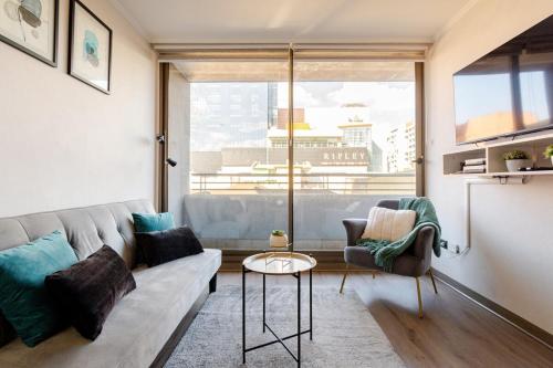 a living room with a couch and a large window at Departamento céntrico con estacionamiento in Concepción