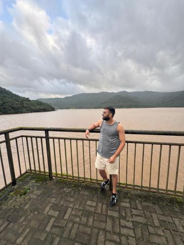 a man standing next to a fence near a body of water at Kinaara farms in Dāsna