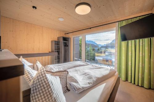 a bedroom with a bed and a large window at TinyHome Singer - inclusive private Sauna in Ehenbichl