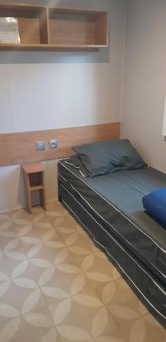 ein Schlafzimmer mit einem Bett mit einem hölzernen Kopfteil in der Unterkunft MOBIL HOME DE GRAND CONFORT-3ch Climatisées-CAMPING BONNE ANSE 509- 4 étoiles LA PALMYRE in Les Mathes