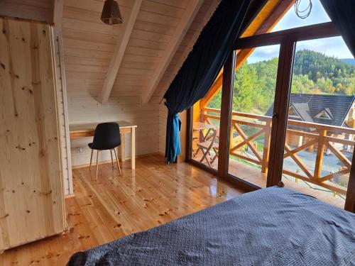 a bedroom with a bed and a large window at Blisko natury - chatki z sauną w Zawoi in Zawoja