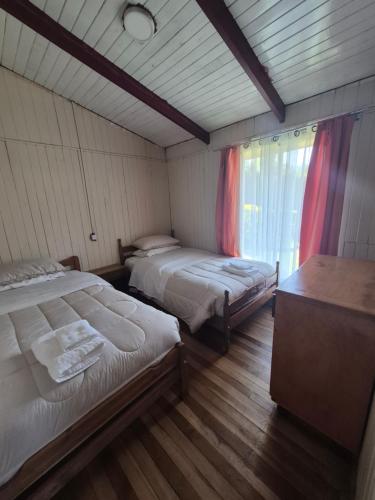 a room with two beds in a room with a window at Cabana El Sauce in San Patricio