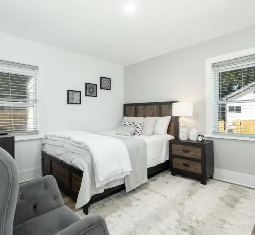 Un dormitorio blanco con una cama y una silla. en Encanto del sur, en Charleston