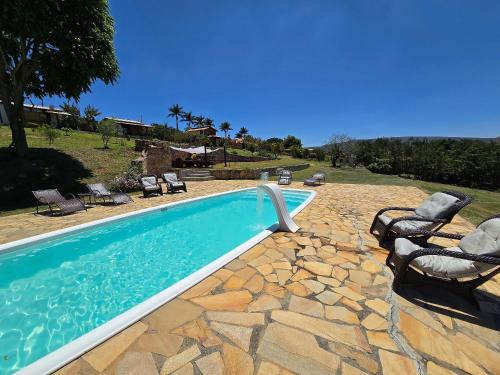 a swimming pool with a group of chairs around it at Chalés Vila Carrancas - Ao lado do centro com piscina, cozinha completa e muita tranquilidade in Carrancas