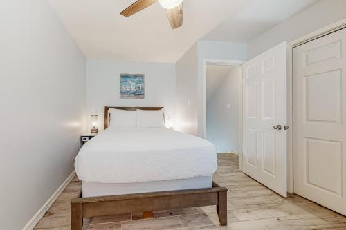 a white bedroom with a bed and a white door at Leeward Cove A8 in Padre Island