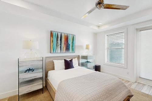 a white bedroom with a bed and a ceiling fan at Padre Villa 104 in Padre Island