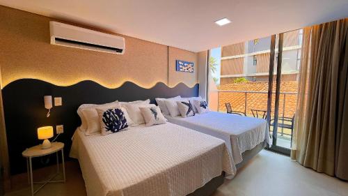 a bedroom with two beds and a balcony at Setai Aquamaris Luxo - By Almare in Tambaú