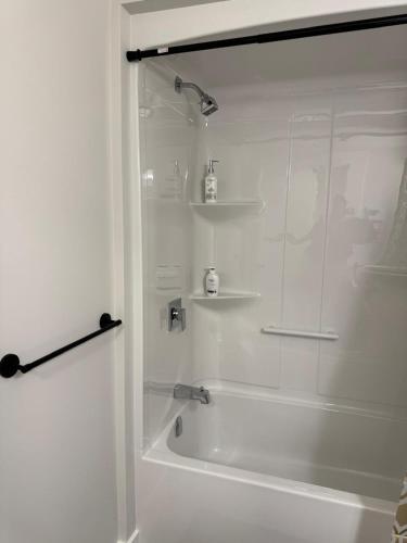 a white bathroom with a shower and a bath tub at Comfy Apartment in Moncton
