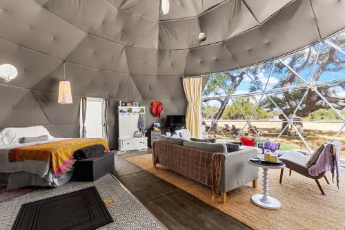 a bedroom in a dome tent with a bed and couch at The Dome in Cloptins Crossing