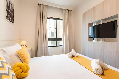 a bedroom with a white bed with a flat screen tv at MP/1212-Flat completo no Hotel Mercure Pinheiros in Sao Paulo