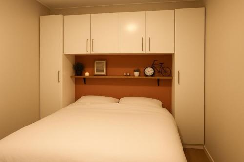 a bedroom with a large bed with white cabinets at Nature Escape Veluwe Chalet in Putten