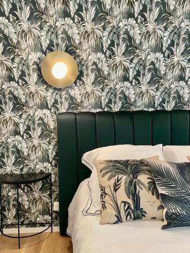 een slaapkamer met een groen hoofdeinde en palmbomenbehang bij Charmante petite maison d'exception classée in Saint-Brieuc