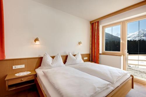 a bedroom with a bed and a large window at Appartements Luegeck in Hollersbach im Pinzgau