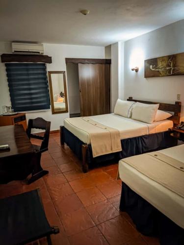 a room with two beds and a table and a desk at Hostal San Francisco in San Cristóbal