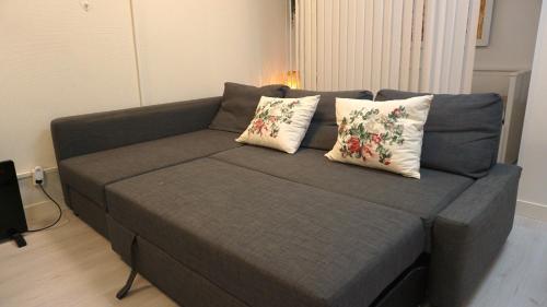 a couch with two pillows on it in a living room at Fresh And Cozy Little House 30km In Täby in Stockholm