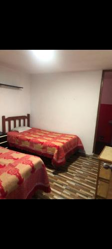 ein Schlafzimmer mit zwei Betten mit roten Decken auf dem Boden in der Unterkunft Departamento amoblado in Huaraz