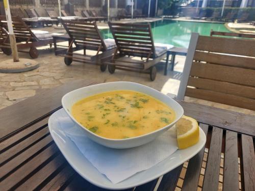 eine Schüssel Suppe auf einem Teller mit einer Scheibe Brot in der Unterkunft Семеен хотел Звезда in Sŭdievo