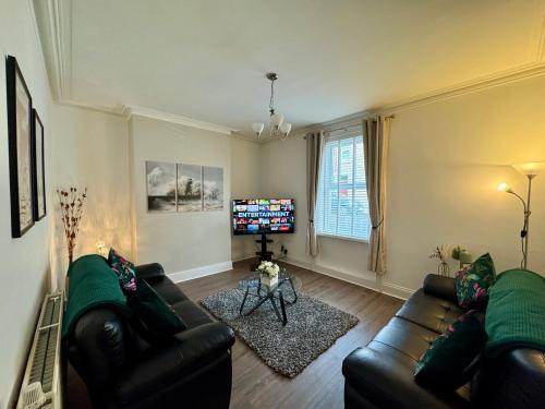 a living room with a couch and a tv at Tynemouth Haven, Luxurious three bed family home in Tynemouth