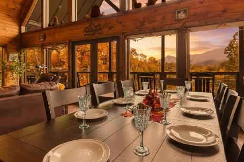 a dining room with a table with plates and glasses at New Luxury Lodge - Gatlinburg - Mountain View! in Gatlinburg