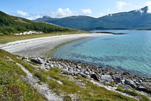 ボードーにあるLeilighet i i vakre Skivika, Bodø Gratis parkering og rolige omgivelser nært sentrumの岩と山を背景にした水のビーチ
