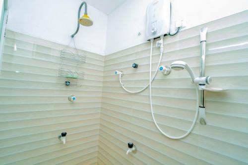 a shower in a bathroom with striped walls at Joy Villa Garden in Batticaloa