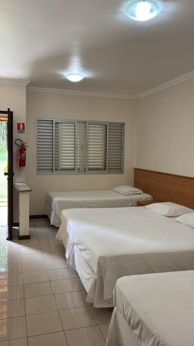 a group of four beds in a room at Hotel Lago Alphaville in Apucarana