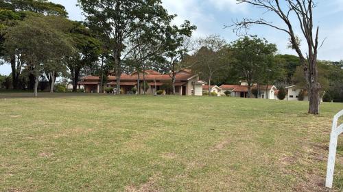 a house in a field with a tree in the yard at Hotel Lago Alphaville in Apucarana