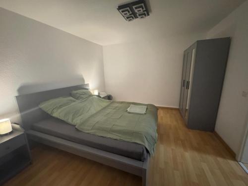 a bedroom with a bed with a green blanket at Zentrales Apartment mit Netflix, Kaffee & Parkplätzen in Paderborn