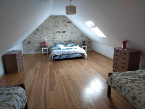 a attic bedroom with two beds and a stone wall at Au repos du Dourmeur in Saint-Évarzec