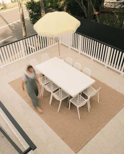 a woman walking past a white table with an umbrella at Heart of Milton 4b2b AC 2Tvs Private Parking walk to Suncorp Stadium in Brisbane