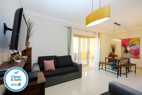 a living room with a black couch and a tv at Patio do Convento Apartments in Lagos