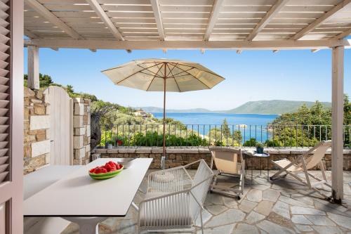 a patio with a table and an umbrella at Lithea Villas and Studios by the Sea in Aghios Petros Alonissos