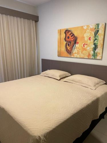 a bed in a bedroom with a painting on the wall at Park Veredas Apto 705 in Rio Quente
