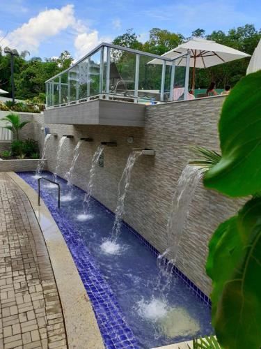a pool with three water fountains on a brick wall at Park Veredas Apto 705 in Rio Quente