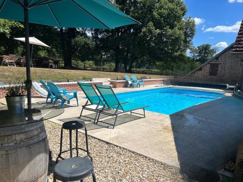 a swimming pool with blue chairs and an umbrella at Gîte 2, ouvriers, vacances 1h45 de Paris in Nouan-le-Fuzelier
