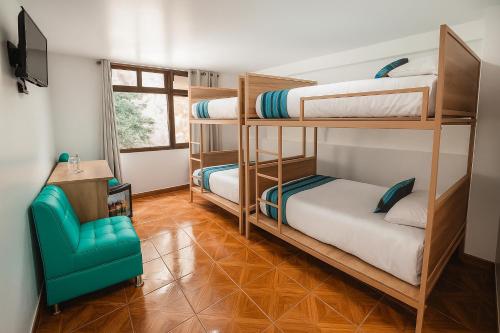 a room with three bunk beds and a blue chair at Casa Andora in Machu Picchu