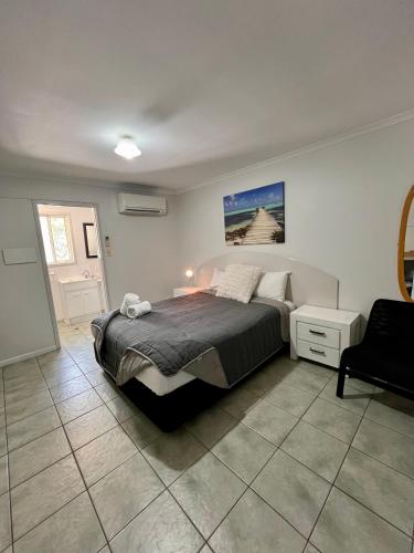 a bedroom with a bed and a chair in it at Agnes Palms Motel in Agnes Water