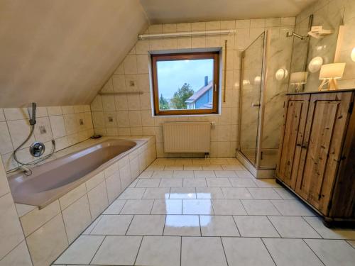 a bathroom with a tub and a shower and a window at Eulennest im Ferienhaus an der Holzecke in Schnelldorf