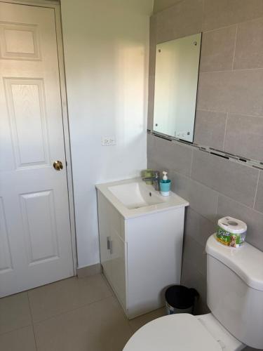 a bathroom with a toilet and a sink and a mirror at Portmore Country Club Cozy1Bedroom Retreat in Portmore