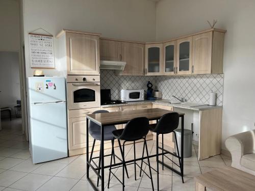 a kitchen with white appliances and a table and chairs at Petite maison cœur de ville de La Teste de Buch in La Teste-de-Buch