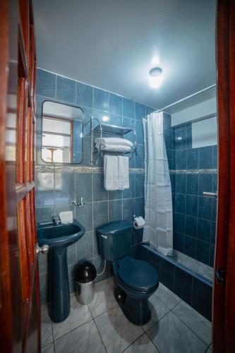 a blue tiled bathroom with a toilet and a sink at Casa Andora in Machu Picchu