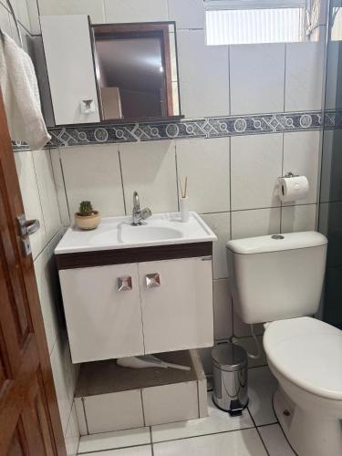 a white bathroom with a toilet and a sink at Kitnet ao lado do centro in Itabira