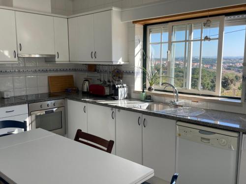a kitchen with white cabinets and a large window at Casa da Foz do arelho in Nadadouro