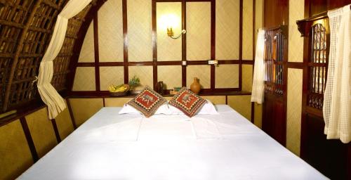 a bedroom with a white bed with two pillows at Spice Coast Cruises - Houseboat, A CGH Earth Experience in Alleppey