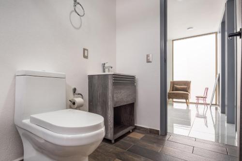 a white bathroom with a toilet and a fireplace at Casa Adul Chignahuapan in Chignahuapan