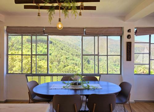 a dining room with a blue table and chairs and windows at Adcasinha em Arganil in Adcasal