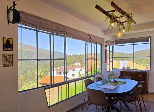 a dining room with a table and a large window at Adcasinha em Arganil in Adcasal
